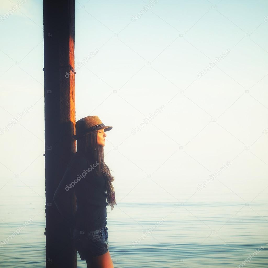 Casual girl relaxing under the pier in a sea water, enjoy sunset light and breathing air.