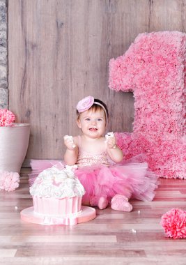 Cute baby girl eating first birthday cake. clipart