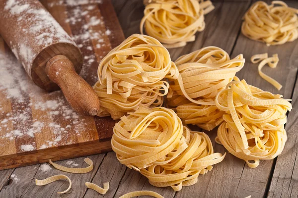 Homemade tagliatelle. Raw pasta on the wooden table — Stock Photo, Image