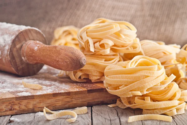 Ev yapımı tagliatelle. Ahşap masa üstünde pişmemiş makarna