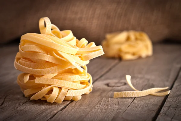 Homemade tagliatelle. Uncooked pasta on the wooden table — Stock Photo, Image