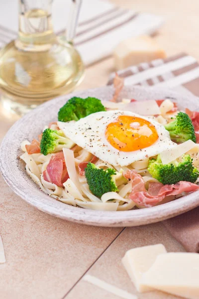 Tagliatelle pasta med broccoli, skinka och stekt ägg. — Stockfoto