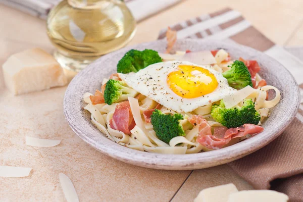 Tagliatelle pasta with broccoli, prosciutto and fried egg. — Stock Photo, Image