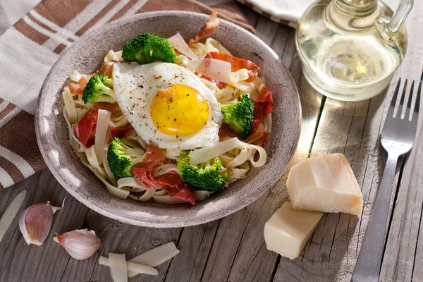 Tagliatelle pasta med broccoli, skinka och stekt ägg. — Stockfoto