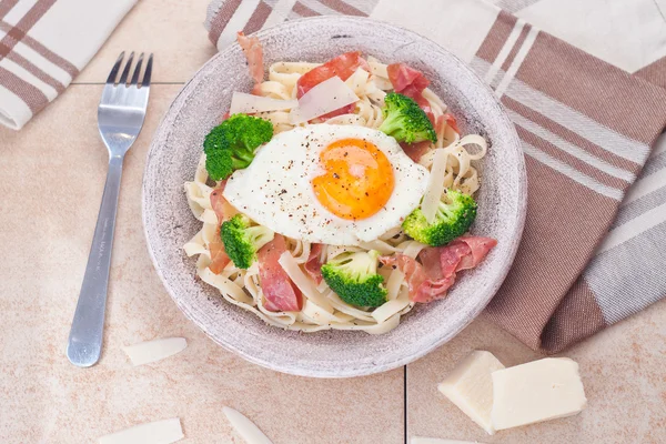 Tagliatelle pasta med broccoli, skinka och stekt ägg. — Stockfoto