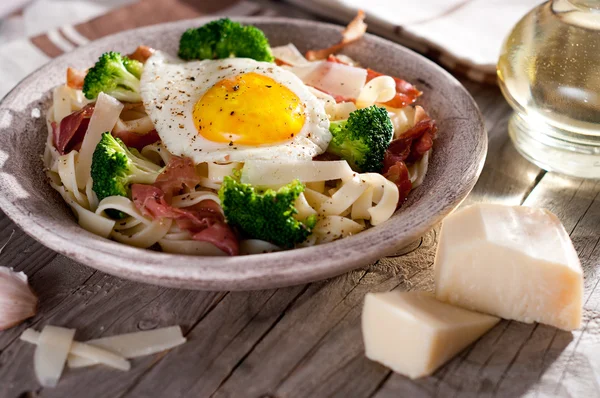 Tagliatelle pasta with broccoli, prosciutto and fried egg. — Stock Photo, Image