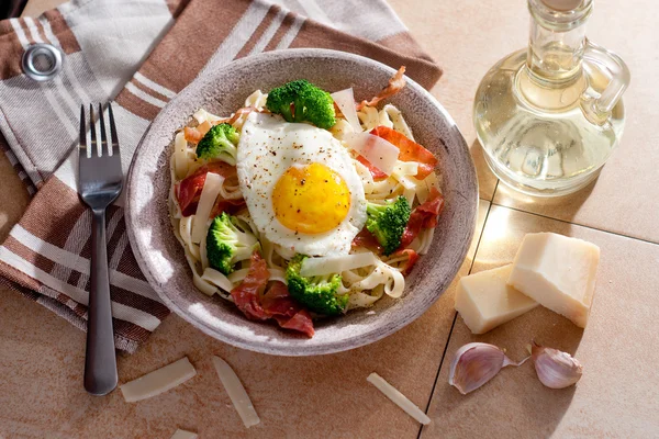 Tagliatelle pasta med broccoli, skinka och stekt ägg. — Stockfoto