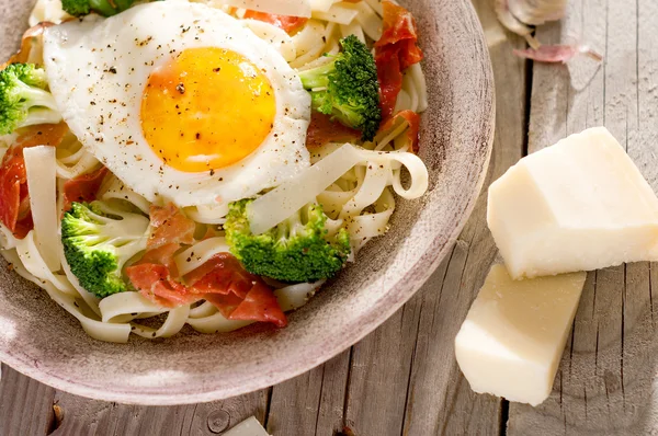 Tagliatelle pasta med broccoli, skinka och stekt ägg. — Stockfoto