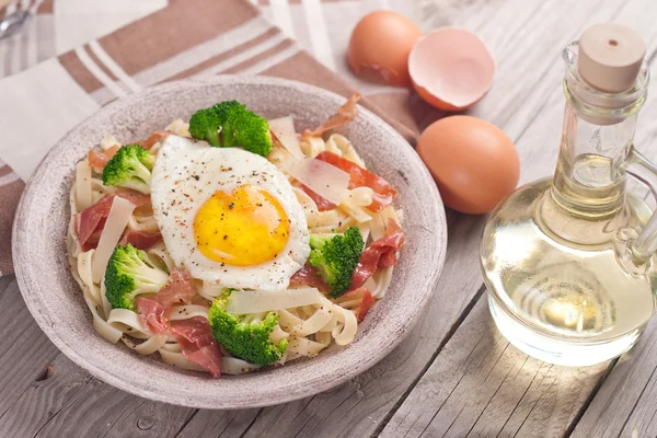 Tagliatelle pasta med broccoli, skinka och stekt ägg. — Stockfoto