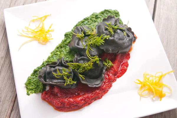 Black ravioli with spinach and garlic sauce tomato. — Stock Photo, Image