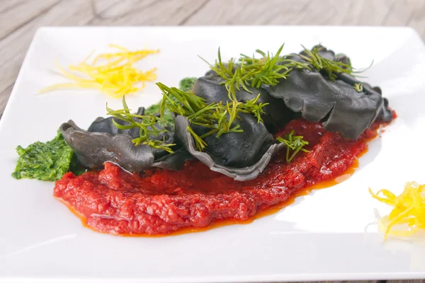 Black ravioli with spinach and garlic sauce tomato. — Stock Photo, Image