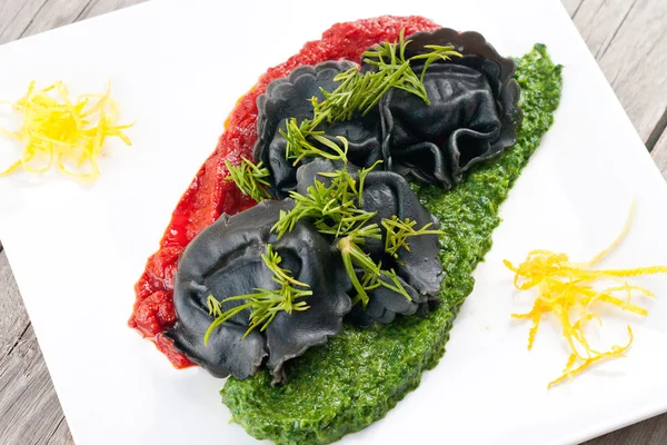 Black ravioli with spinach and garlic sauce tomato. — Stock Photo, Image