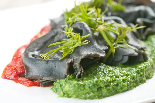 Black ravioli with spinach and garlic sauce tomato. — Stock Photo, Image