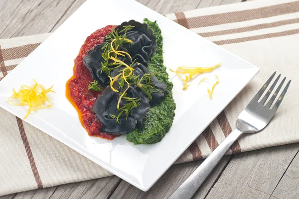 Black ravioli with spinach and garlic sauce tomato. — Stock Photo, Image