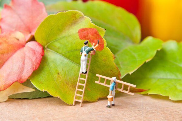 Little people paint leaf on autumn colors. The concept of teamwo