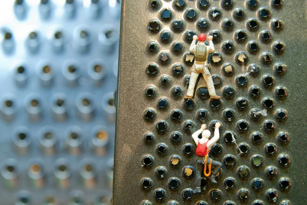 Des petits hommes grimpant sur une râpe de cuisine. Concept sport, loisir — Photo