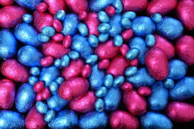 Yığınla renkli ve farklı boyutlarda renkli folyo paketlenmiş mavi ve pembe paskalya yumurtaları.. 