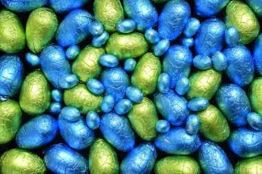 Yığınla renkli ve farklı boyutlarda çikolatalı paskalya yumurtaları mavi, sarı ve limon yeşili.. 