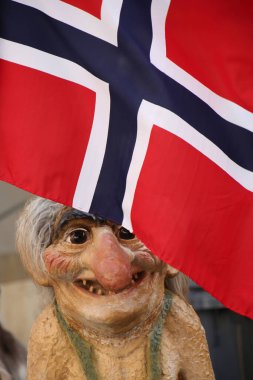 Norveç 'in kırmızı, beyaz ve mavi bayrağının altında duran geleneksel Norveç folkloru olan Trol heykeli. 