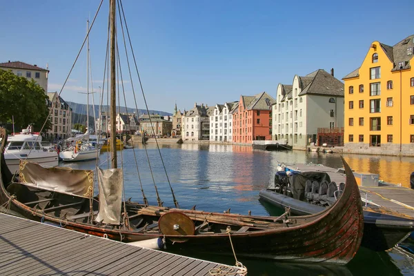一条木制的维京船停泊在挪威阿莱松德市中心的码头上 市区的背景中有许多漂亮的五彩斑斓的建筑物 图库照片