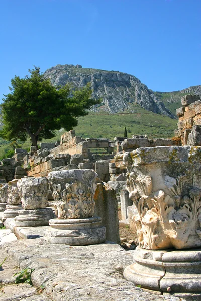 Las cimas de las columnas corintias se encuentran entre las ruinas de Corinto, Grecia — Foto de Stock