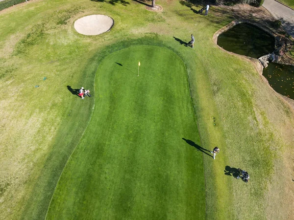 Luftaufnahme von Golfspielern um Fahnenmarke in Loch auf Golfplatz — Stockfoto