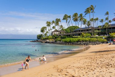 Turist, Maui, Hawaii 'de beyaz kum ve kristal berrak suyla tropikal plajın tadını çıkarıyor.
