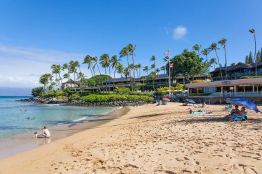 Turist, Maui, Hawaii 'de beyaz kum ve kristal berrak suyla tropikal plajın tadını çıkarıyor.