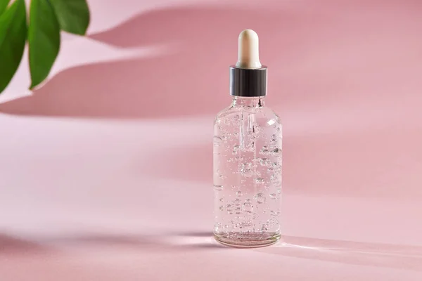 Pembe arka planda cam bir şişede yaşlanma önleyici serum. Kolajen ve peptidli yüz sıvısı serumu. Güzel, sağlıklı bir cilt için doğal cilt bakımı.