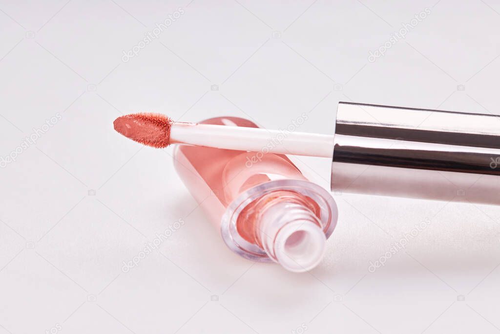 Tube of liquid lipstick gloss with applicator isolated on white background