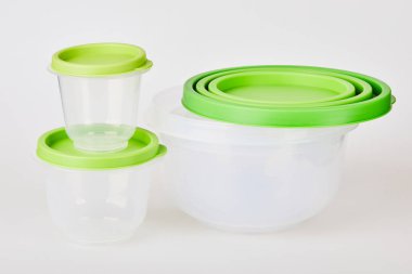 Beyaz arka planda yeşil kapaklı saydam plastik gıda saklama kapları.