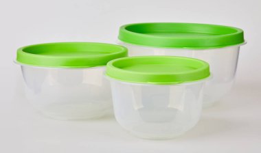 Beyaz arka planda yeşil kapaklı saydam plastik gıda saklama kapları.