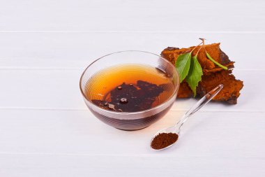 Beyaz arka planda izole edilmiş cam bir kasede doğal sıcak Chaga mantar çayı, yakın plan. Inonotus Obliquus. 