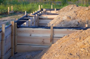 Bir kulübe için ahşap beton döşeme temeli. Yeni ev, bina, detaylar ve çelik parmaklıklar ve tel çubuklarla takviye birlikleri, çimento dökmeye hazırlanıyor.