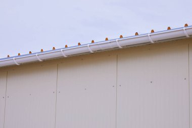 Beyaz plastik yağmur oluğu sistemi. Kanalizasyon borusu dış yüzeyde. Sandviç panelinin arka planı 