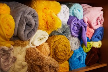 Pile of vibrant colorful rolled up fleece textile. Fabric for toys design