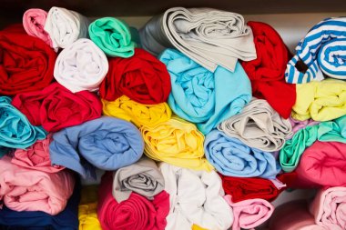 Pile of vibrant colorful rolled up fleece textile. Fabric for toys design