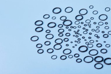 Black hydraulic and pneumatic o-ring seals of different sizes a blue background. Rubber rings. Sealing gaskets for hydraulic joints. Rubber sealing rings for plumbing. Top view