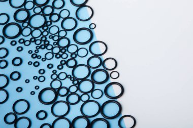 Black hydraulic and pneumatic o-ring seals of different sizes a blue and white background. Rubber rings. Sealing gaskets for hydraulic joints. Rubber sealing rings for plumbing. Top view