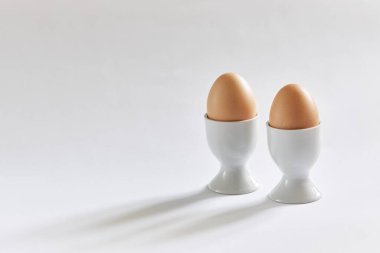 Beyaz arka planda iki bej yumurta kabı..