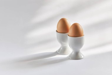 Beyaz arka planda iki kahverengi yumurta ve güzel gölgeler.