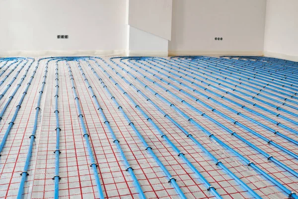 Blue plastic pipes of underfloor heating indoors of a new residential house. Underfloor heating.