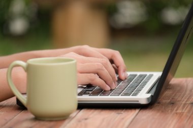 Ahşap masa açık, seçici odak parmakları üzerinde dizüstü bilgisayar kullanan adam