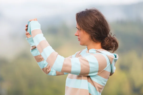 Jovem mulher fotografando a paisagem nas montanhas . — Fotografia de Stock