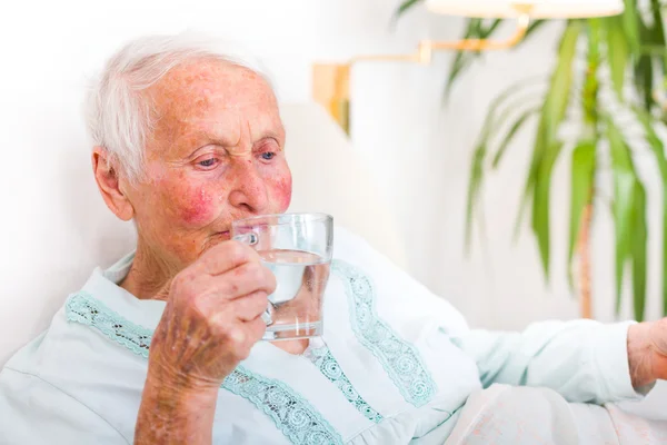 Seniorin trinkt Wasser — Stockfoto