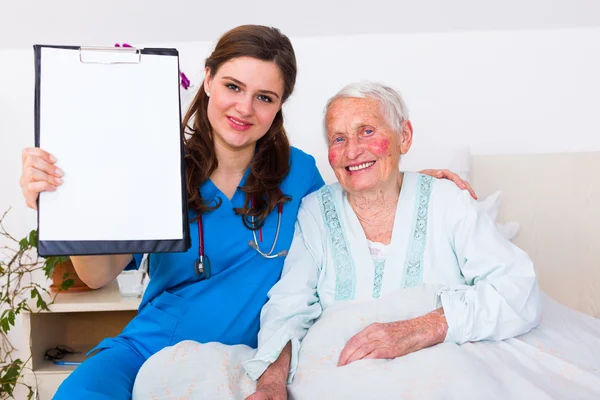 Médico de Geriartric mostrando um registro em branco para a câmera — Fotografia de Stock