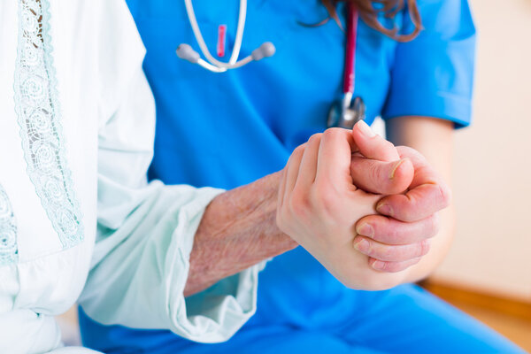 Senior woman holding to the hands of doctor