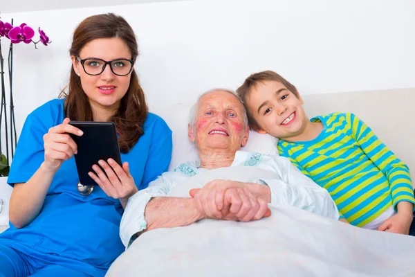 Donna anziana divertirsi con la famiglia e il medico — Foto Stock