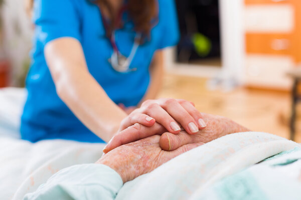 Nurse holding the hand of an elderly woman