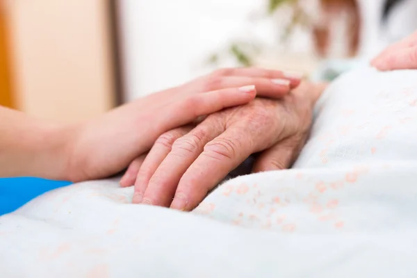 Enfermera sosteniendo la mano de una anciana — Foto de Stock